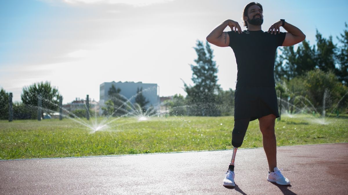 A man with a prosthetic leg exercising on an outdoor track. Empowering and active scene.
